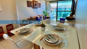 A dining area with a table set for four, surrounded by white chairs.