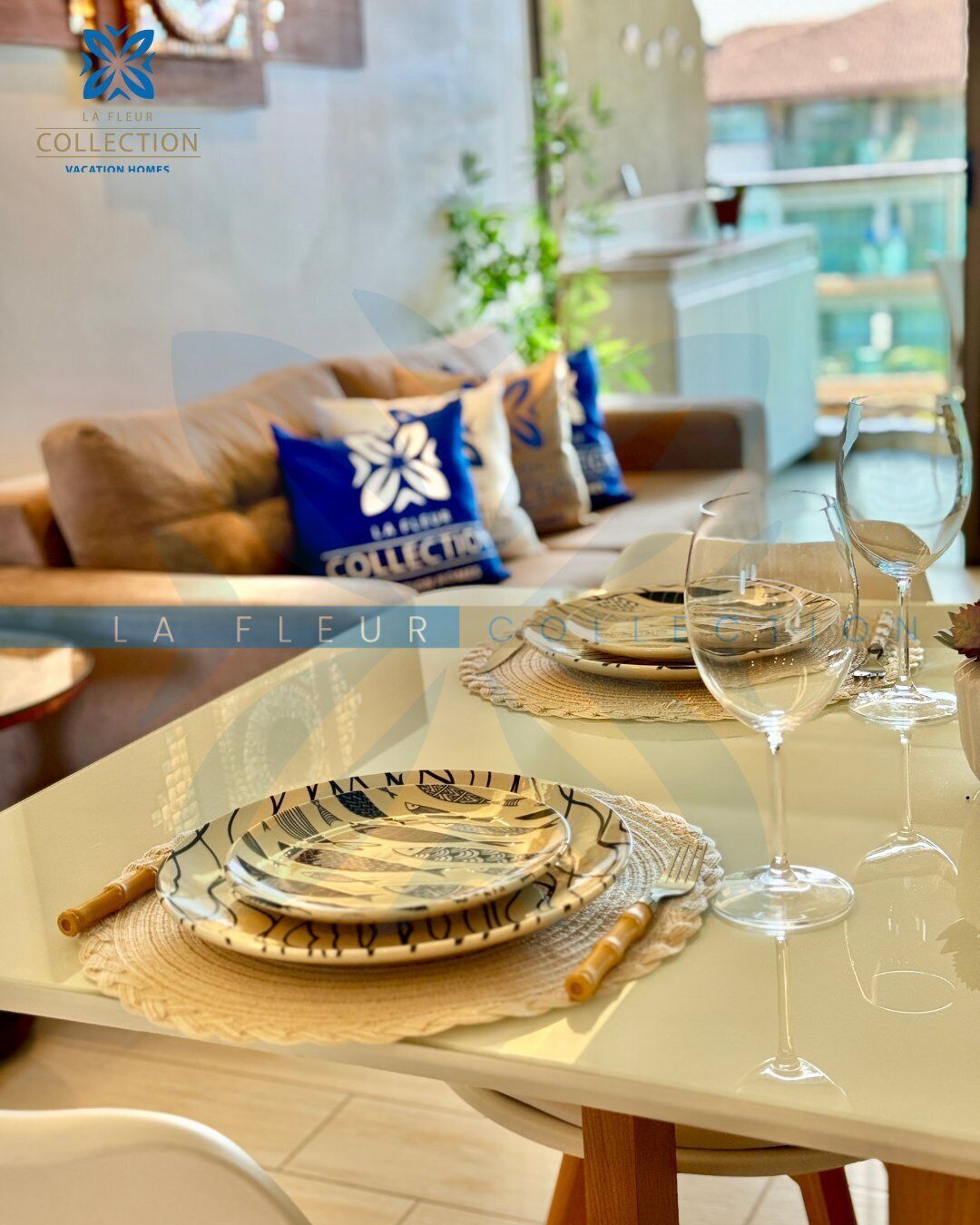 Un coin repas avec une table dressée pour deux personnes, agrémentée d’assiettes décorées et de verres à vin.