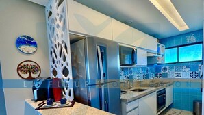A modern kitchen with a granite countertop, stainless steel appliances, and blue-tiled backsplash.