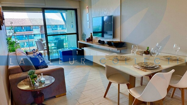 A modern living room with a sofa, a dining table set for four, and a TV mounted on the wall.
