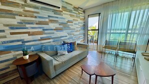 Uma sala de estar moderna com um sofá, uma mesinha e uma varanda com vista.