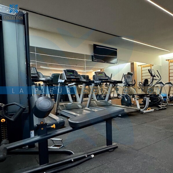 Une salle de sport équipée de tapis de course, de vélos elliptiques et de matériel de musculation.