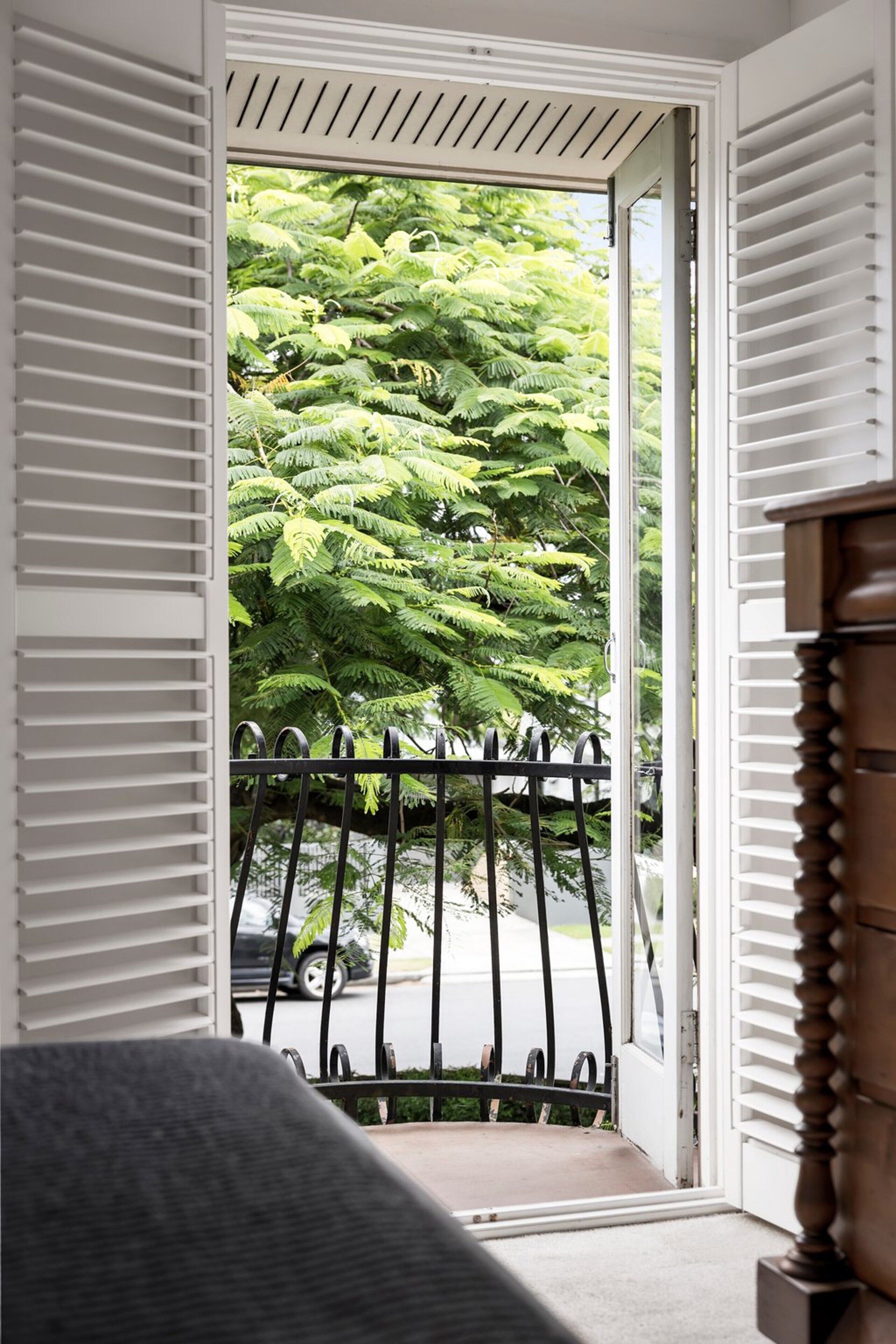 Ein Zimmer mit Blick auf einen Balkon, einem Sessel und einem Holzschrank.