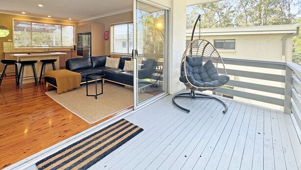 A modern living room with a black leather sofa, a hanging chair, and a wooden deck. - Pet-friendly 2-bed Beach House With Garden & BBQ (Surf Beach)