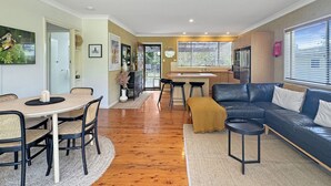 A modern living room with a dining area, a kitchen, and a large window providing natural light. - Pet-friendly 2-bed Beach House With Garden & BBQ (Surf Beach)