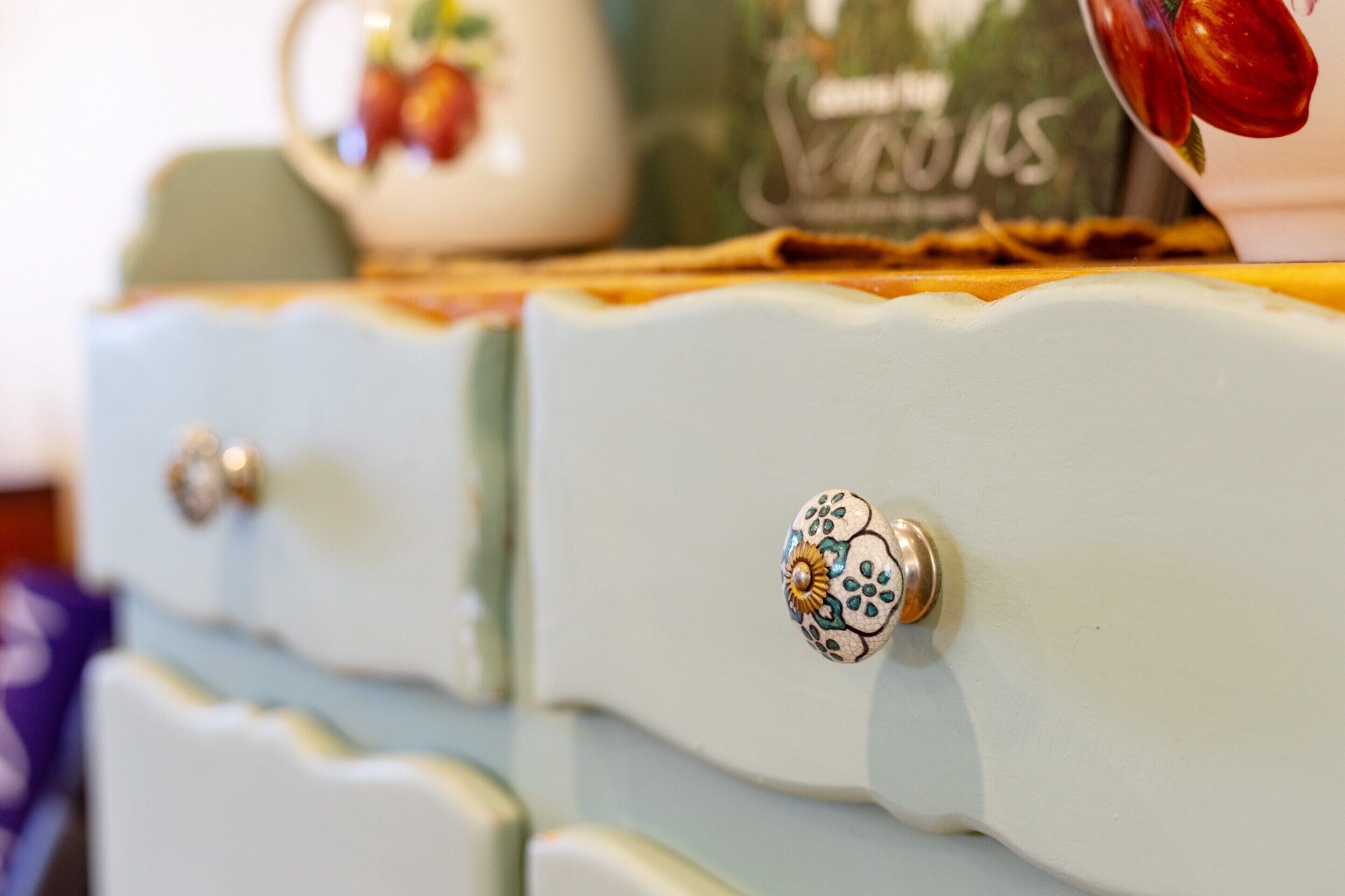 A close-up of a vintage-style dresser with decorative knobs and a floral pattern on the top.