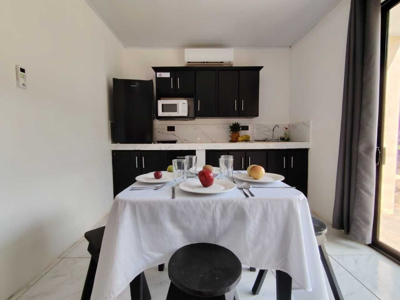 A dining area with a table set for two, a microwave, and dark cabinets in the background.