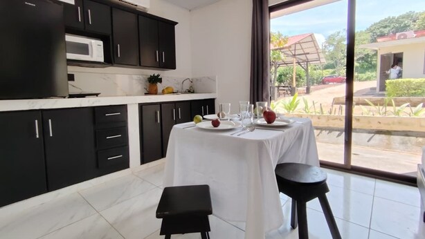 Una cocina moderna con gabinetes negros, una encimera blanca y una mesa para dos comensales.