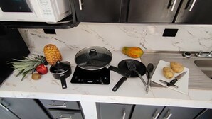 Una cocina equipada con microondas, estufa y distintos utensilios de cocina.