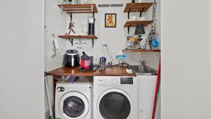 A compact laundry area with a washing machine, a dryer, and a coffee maker on a wooden countertop. - Elegant 2-bed With Pool, Alfresco Dining & Balcony (Canberra)