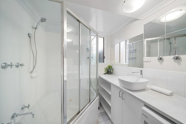 A modern bathroom with a glass shower enclosure, a white sink, and a large mirror. - Stylish 1-bed Stay With Balcony & Study (Canberra)