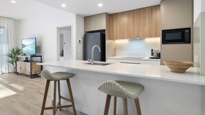A modern kitchen with a white island, stainless steel appliances, and wooden accents. - Stylish 1-bed Apartment With Rooftop Access (Perth)