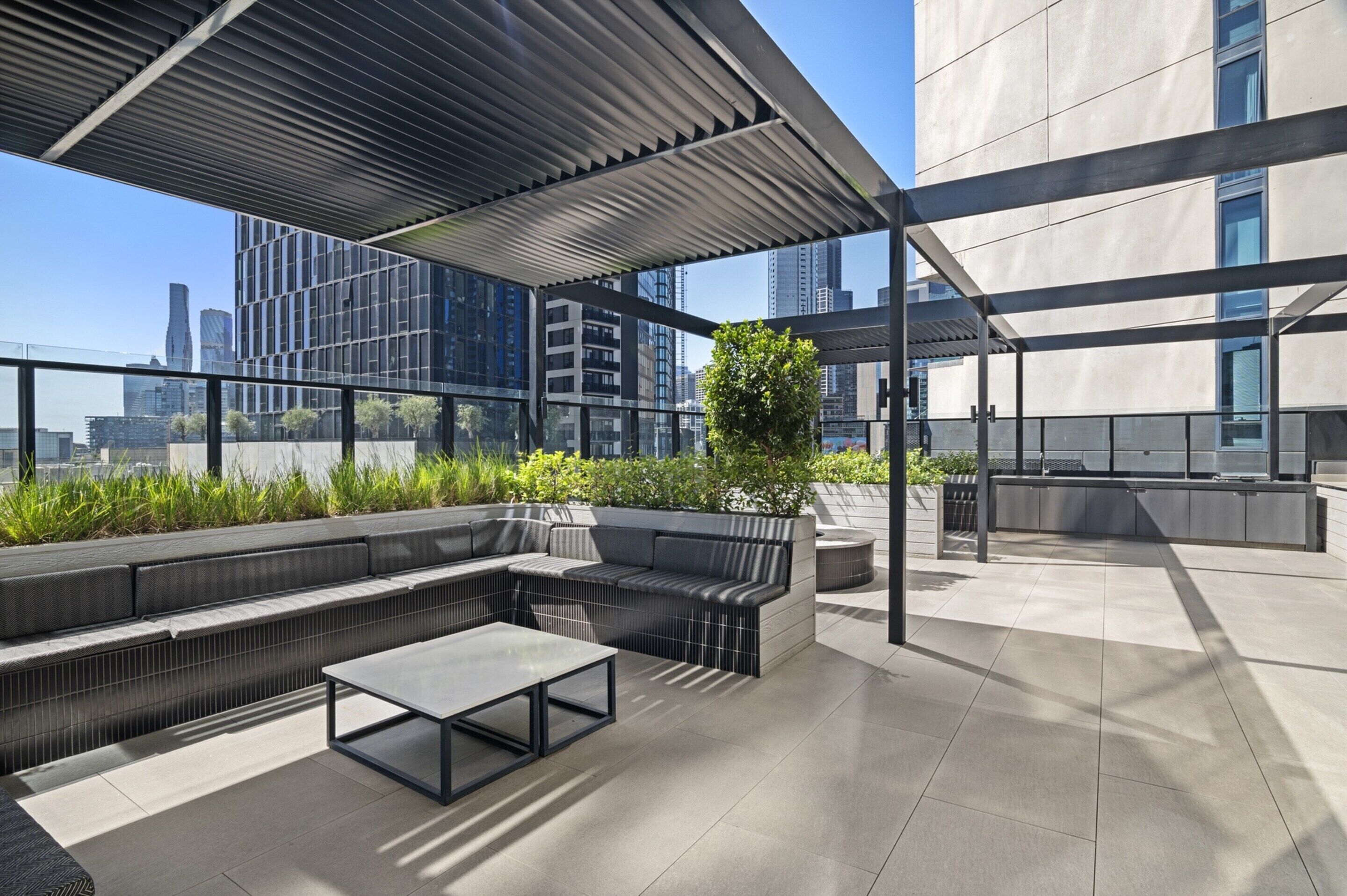 Una terraza en la azotea con una zona de estar moderna, una mesa de vidrio y vistas al horizonte de la ciudad.