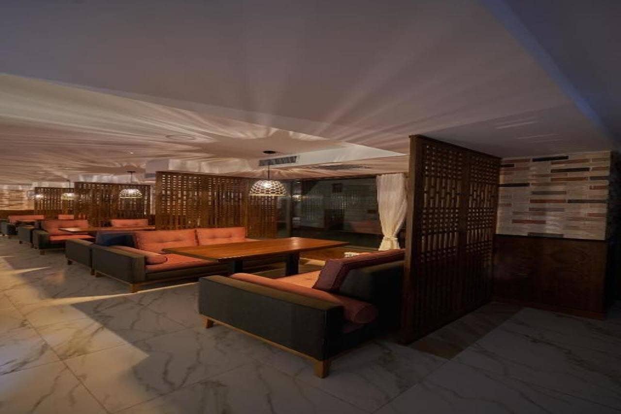 A modern lounge area with seating arrangements and a wooden partition.
