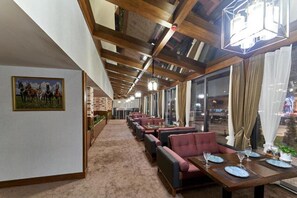 A restaurant with a long counter, multiple seating areas, and a view of the outside through large windows. - Asli Makon Hotel (Tashkent)