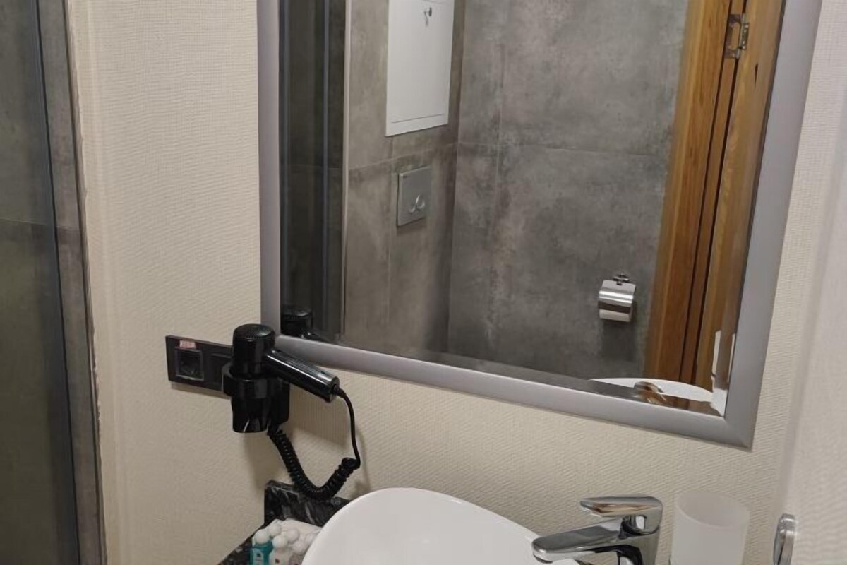 A bathroom with a white sink, a mirror, and a shower area.