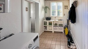 A laundry room with a washing machine, a drying rack, and a cabinet with storage bins. - 2 bedroom gorgeous home in østermarie (Østermarie)