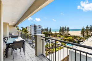 A balcony with a table and chairs, overlooking a beach and a pool. - Oceanfront 3-bed Retreat With Pool-steps to Beach (Sunshine Coast)