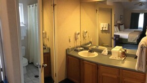 A hotel bathroom with a sink, mirror, and wooden cabinets. - 1 King Bed Jetted Tub (Fresno)