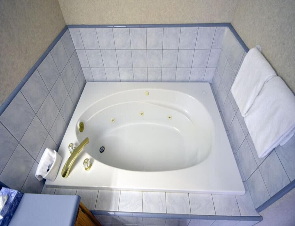 Een badkamer met een witte badkuip, een handdoekhouder en een kleine prullenbak.