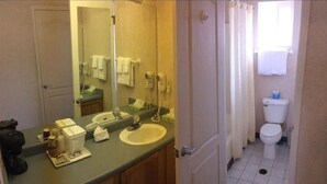 Een badkamer met twee wasbakken, een spiegel, een toilet en een douchegordijn.