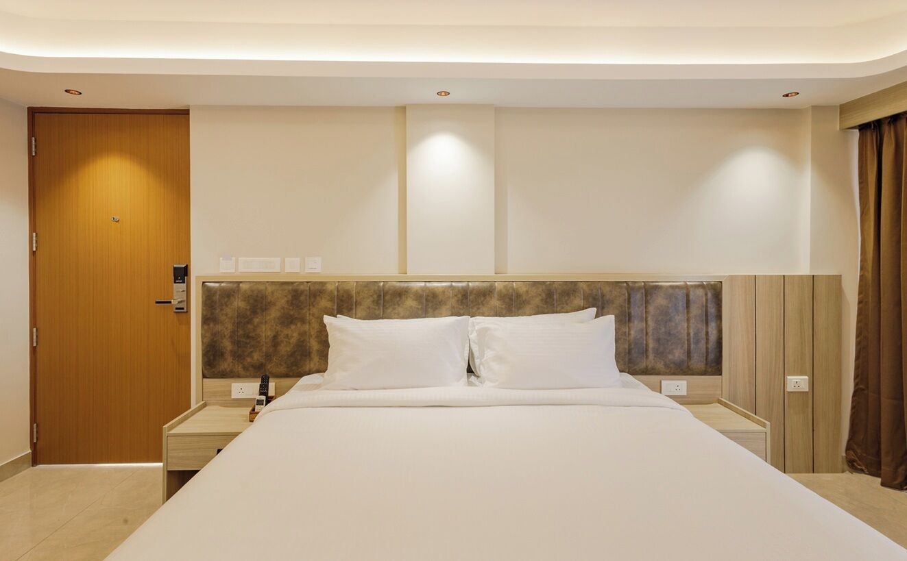 A hotel room with a large bed, wooden headboard, bedside tables, and a door.