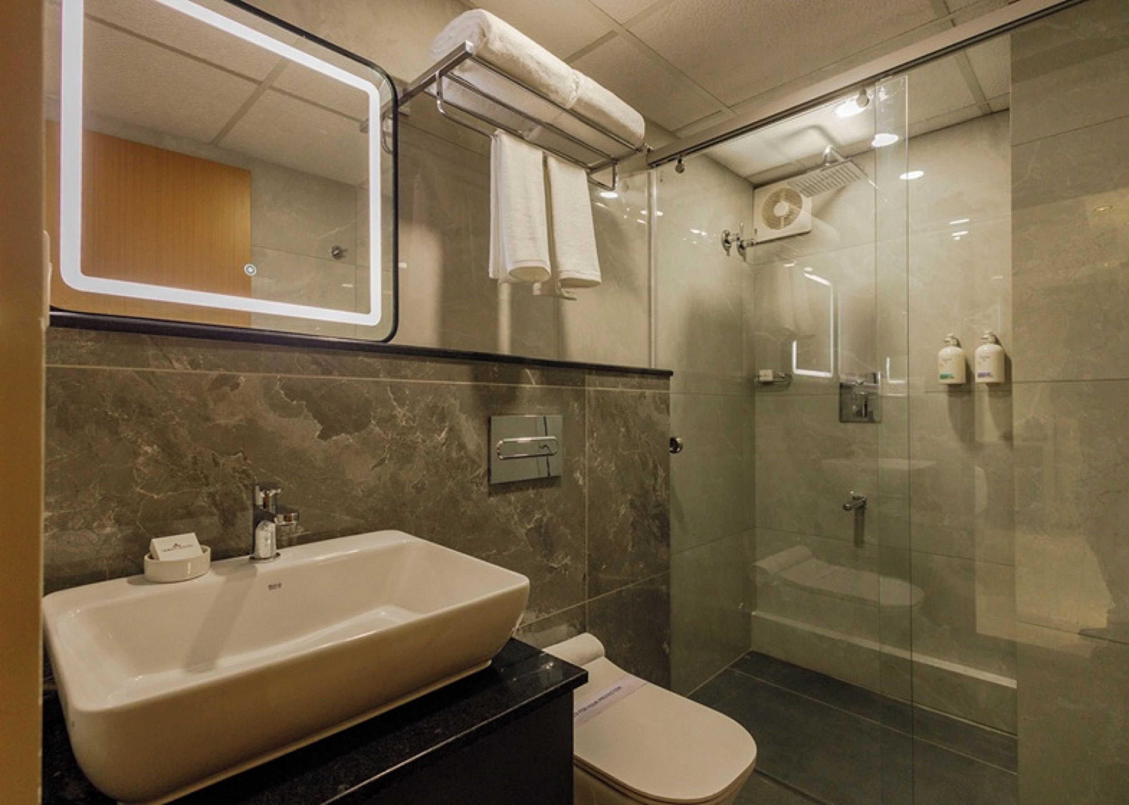 Un baño moderno con un lavamanos grande, inodoro y ducha con mampara de vidrio.