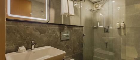 A modern bathroom with a large sink, toilet, and glass-enclosed shower.