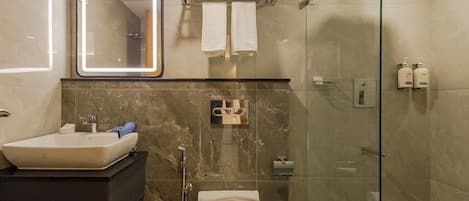 A modern bathroom with a sink, mirror, towel rack, shower, and toilet.