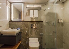 A modern bathroom with a sink, mirror, towel rack, shower, and toilet.