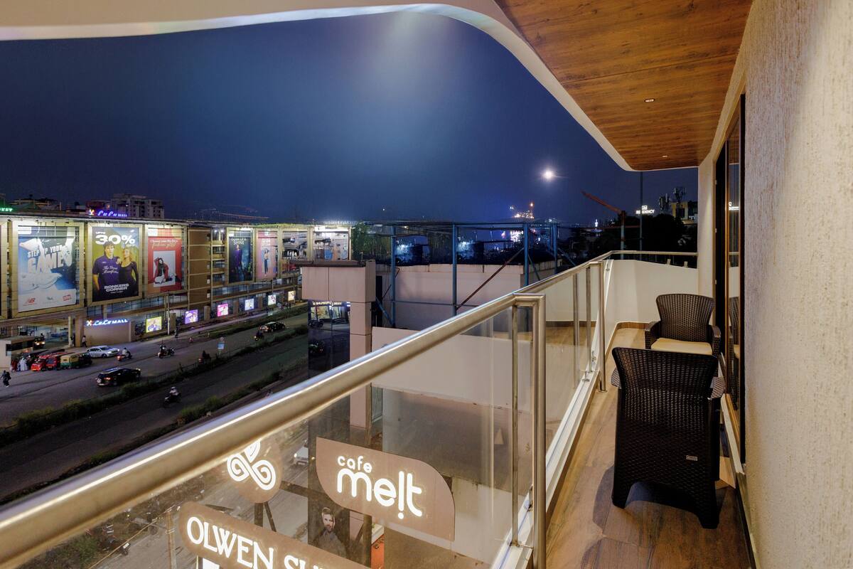 A balcony with a view of a busy street at night, featuring a cafe named 'cafe melt' and a sign for 'OLWEN SL'.