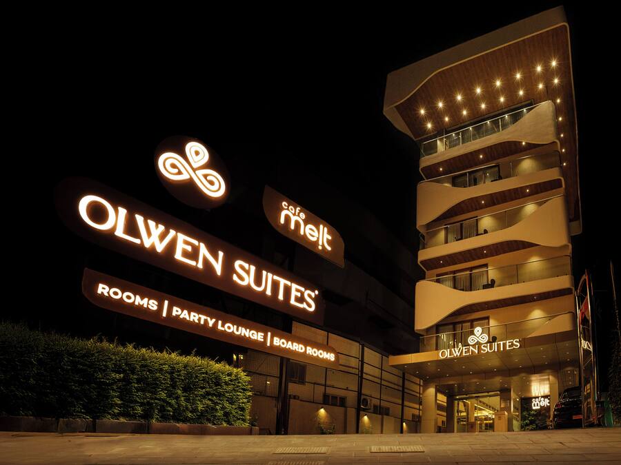 Un hôtel appelé Olwen Suites, dont l’enseigne lumineuse indique l’emplacement des chambres, du salon pour événements et des salles de réunion.