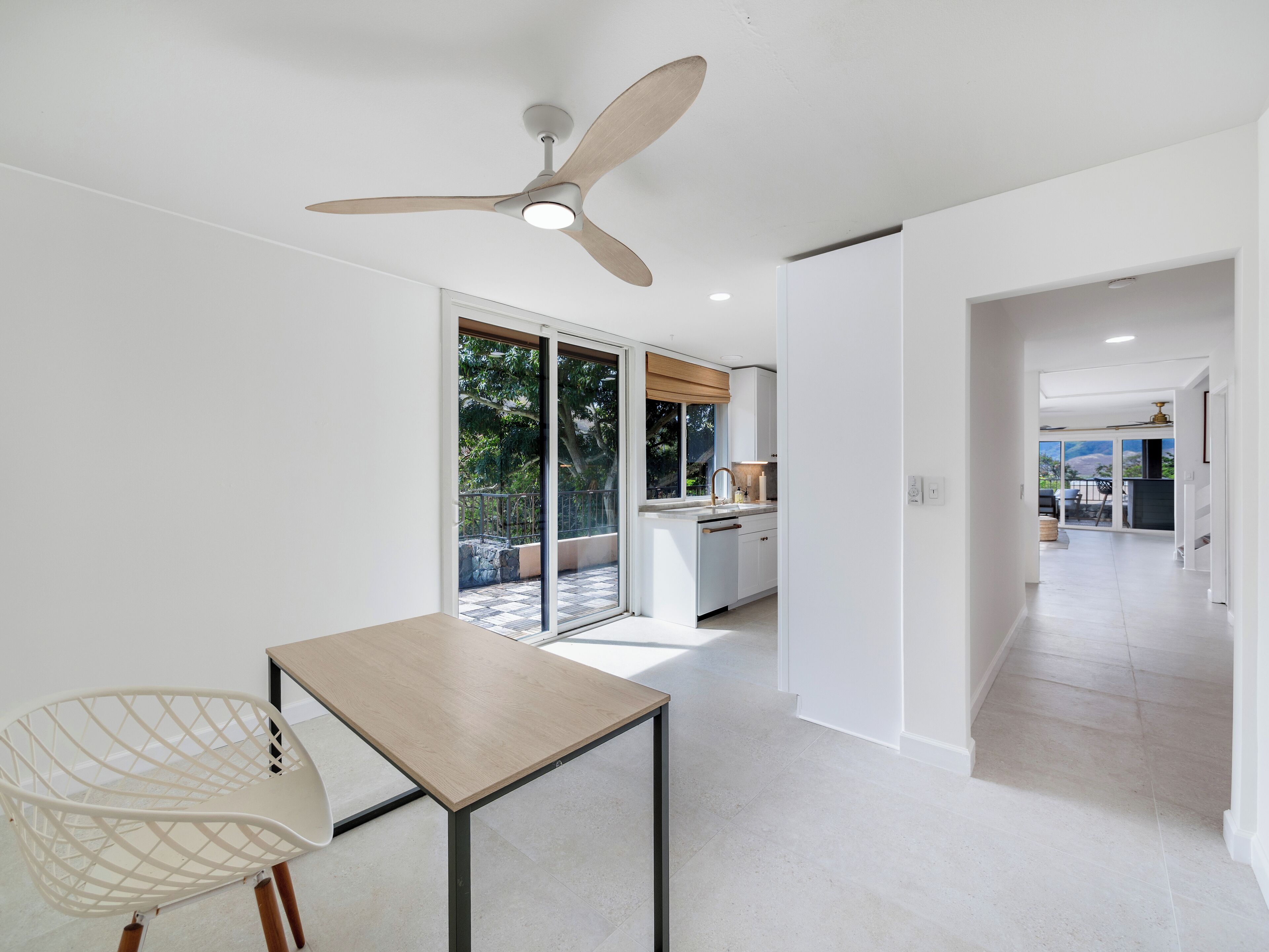 A modern kitchen with a large window, a ceiling fan, and a view of the outdoors.