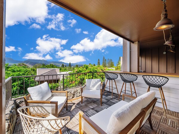 A balcony with wicker furniture, a wooden table, and a hanging light fixture.