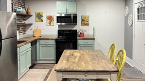 A kitchen with a wooden ceiling, a dining table with chairs, and a patterned rug.