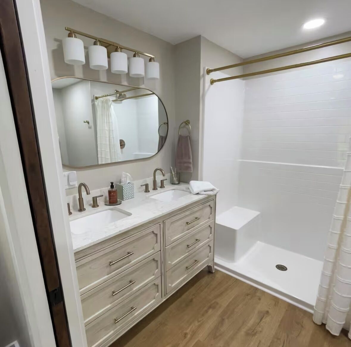 A bathroom with a double sink vanity, a large mirror, a shower with a glass door, and a towel rack.