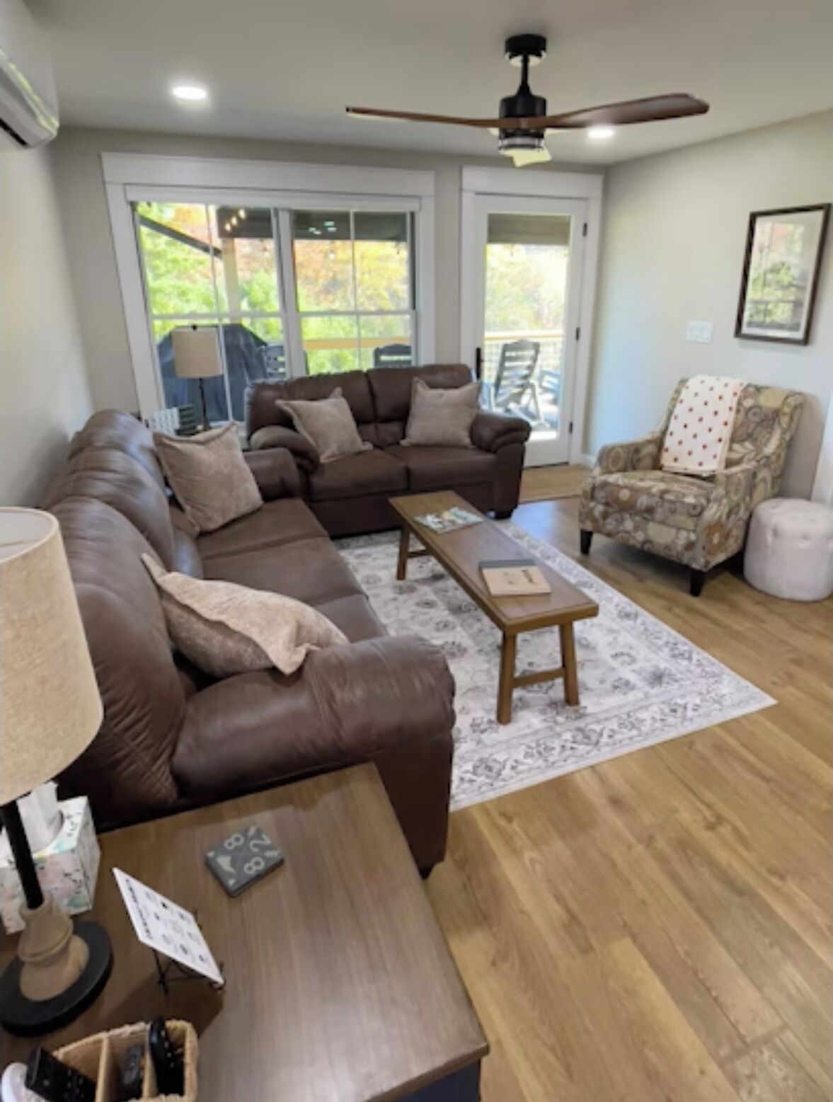 A living room with a brown leather sofa, a wooden coffee table, and a patterned armchair.