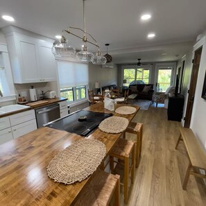 Une cuisine moderne dotée d’un îlot central, de plans de travail en bois et d’un coin repas agrémenté de sets de table en fibres tressées.