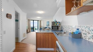 Une cuisine moderne avec des meubles en bois, un four à micro-ondes encastré et un plan de travail bleu.