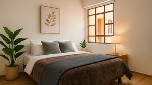 A bedroom with a bed, bedside tables, a window, and a plant. - Espacio premium para grupos, a 2 min del centro (Cuenca)