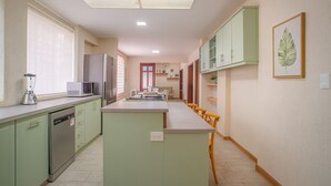 A kitchen with a central island, green cabinets, a dishwasher, and a refrigerator. - Espacio premium para grupos, a 2 min del centro (Cuenca)