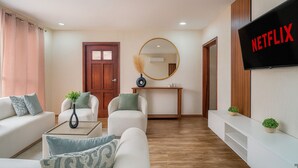A modern living room with a sofa set, a coffee table, a TV mounted on the wall, and a wooden floor. - Espacio premium para grupos, a 2 min del centro (Cuenca)