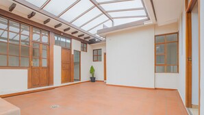 A spacious room with a high ceiling and large windows, featuring a tiled floor and wooden doors. - Espacio premium para grupos, a 2 min del centro (Cuenca)