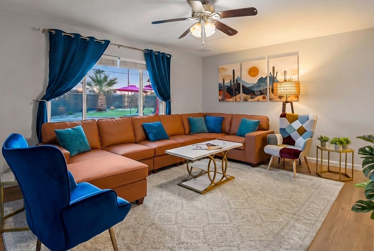 A living room with a sectional sofa, a coffee table, a ceiling fan, and a view of the outdoors.
