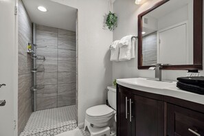 A bathroom with a shower, toilet, and a sink with a mirror.