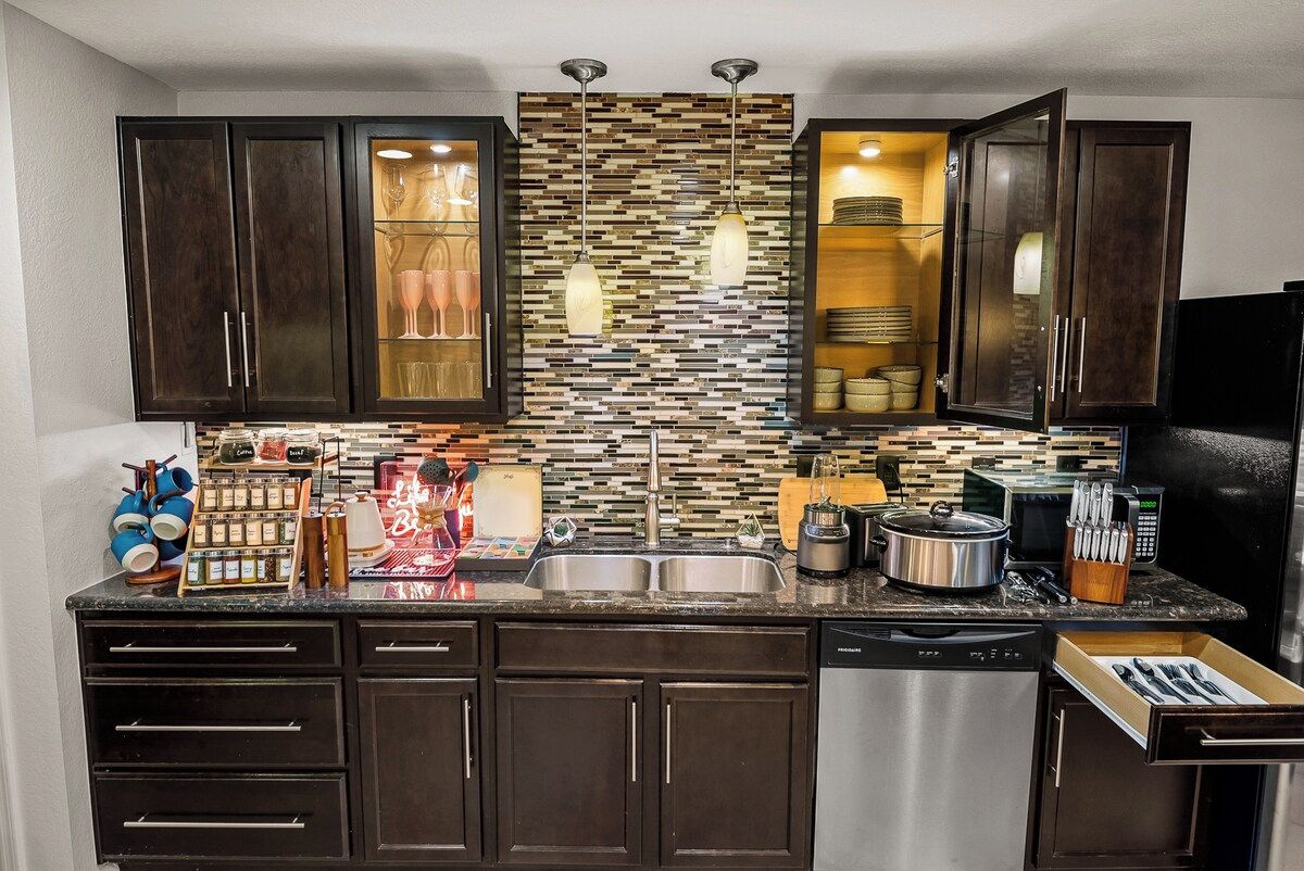 Een moderne keuken met donkerhouten kastjes, een betegelde spatwand, roestvrijstalen apparatuur en een ingebouwde magnetron.