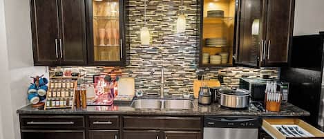 A modern kitchen with dark wood cabinets, a tiled backsplash, stainless steel appliances, and a built-in microwave.
