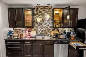Una cocina moderna con armarios de madera oscura, salpicadero de azulejos, electrodomésticos de acero inoxidable y un microondas empotrado.