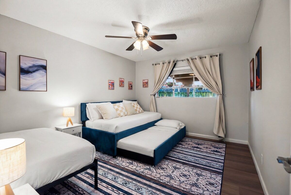 A bedroom with a bed, bedside tables, a ceiling fan, and a window with curtains.
