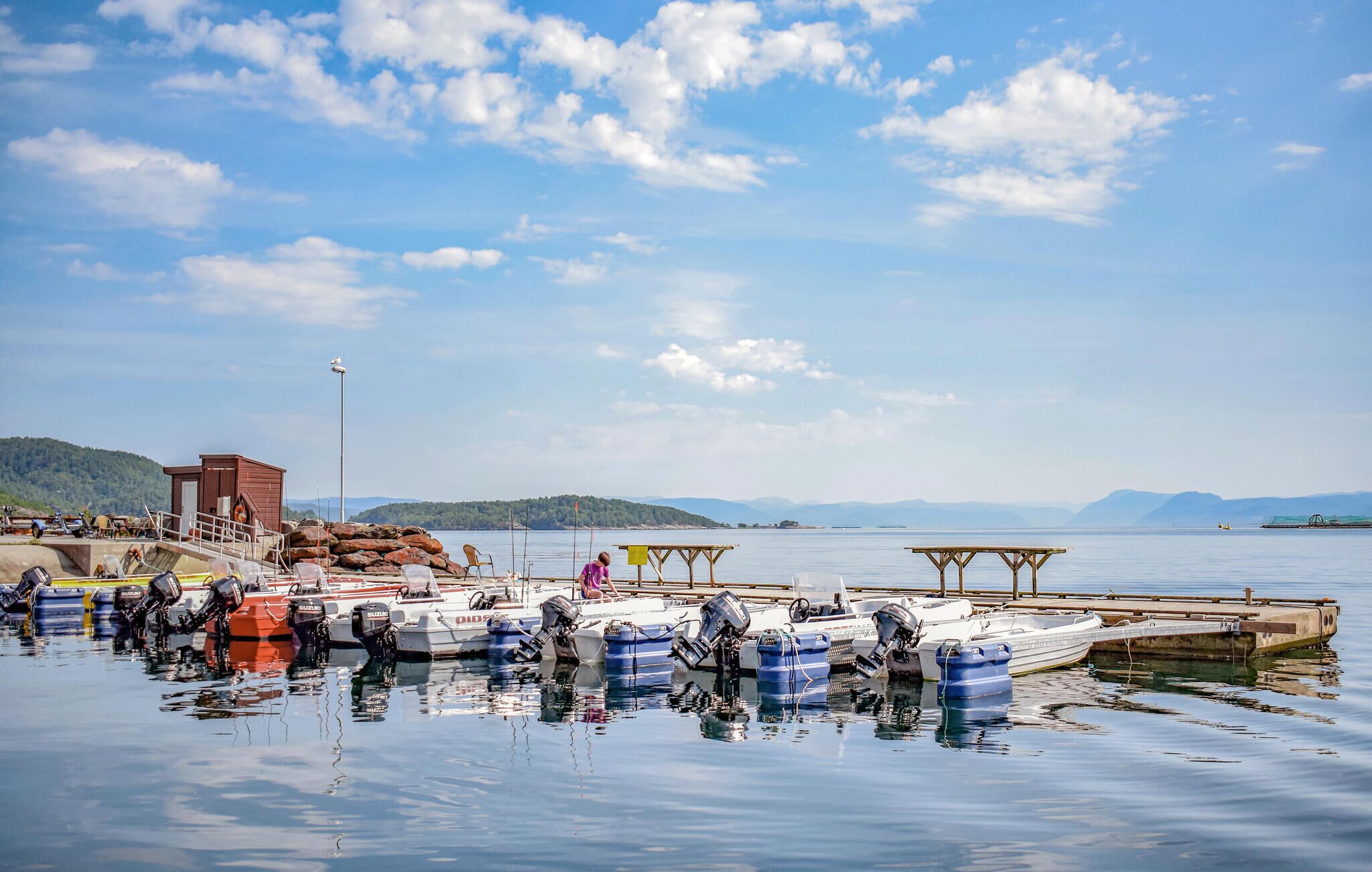 A marina with boats docked, a wooden pier, and a small building.